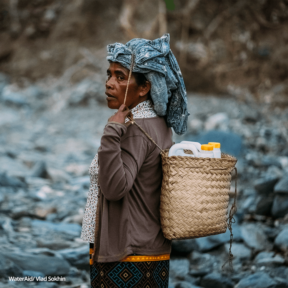 Felisberta, 57, carries two jerry cans on her back, Timor Leste.