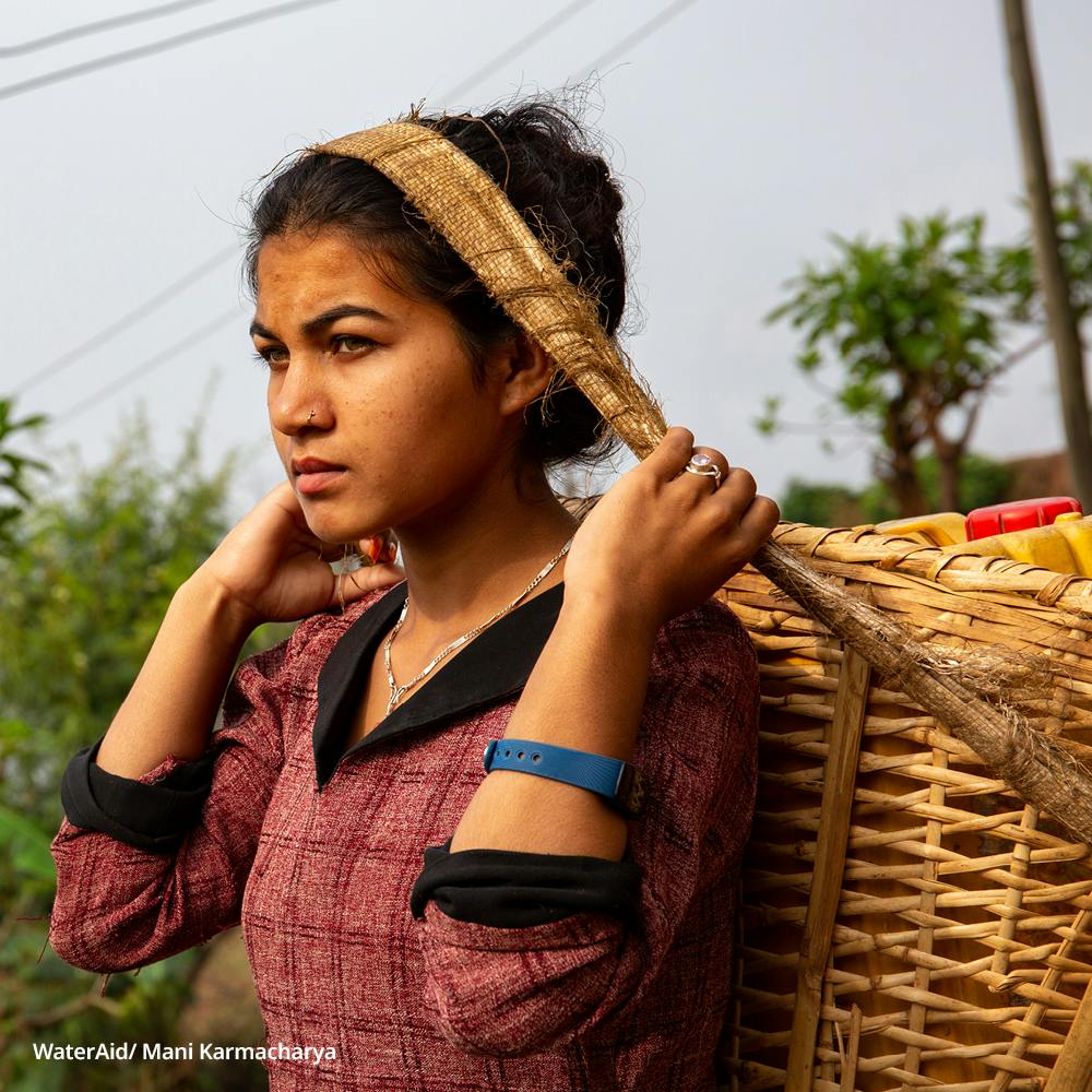 Rekha carrying a water container on her back, Nepal.