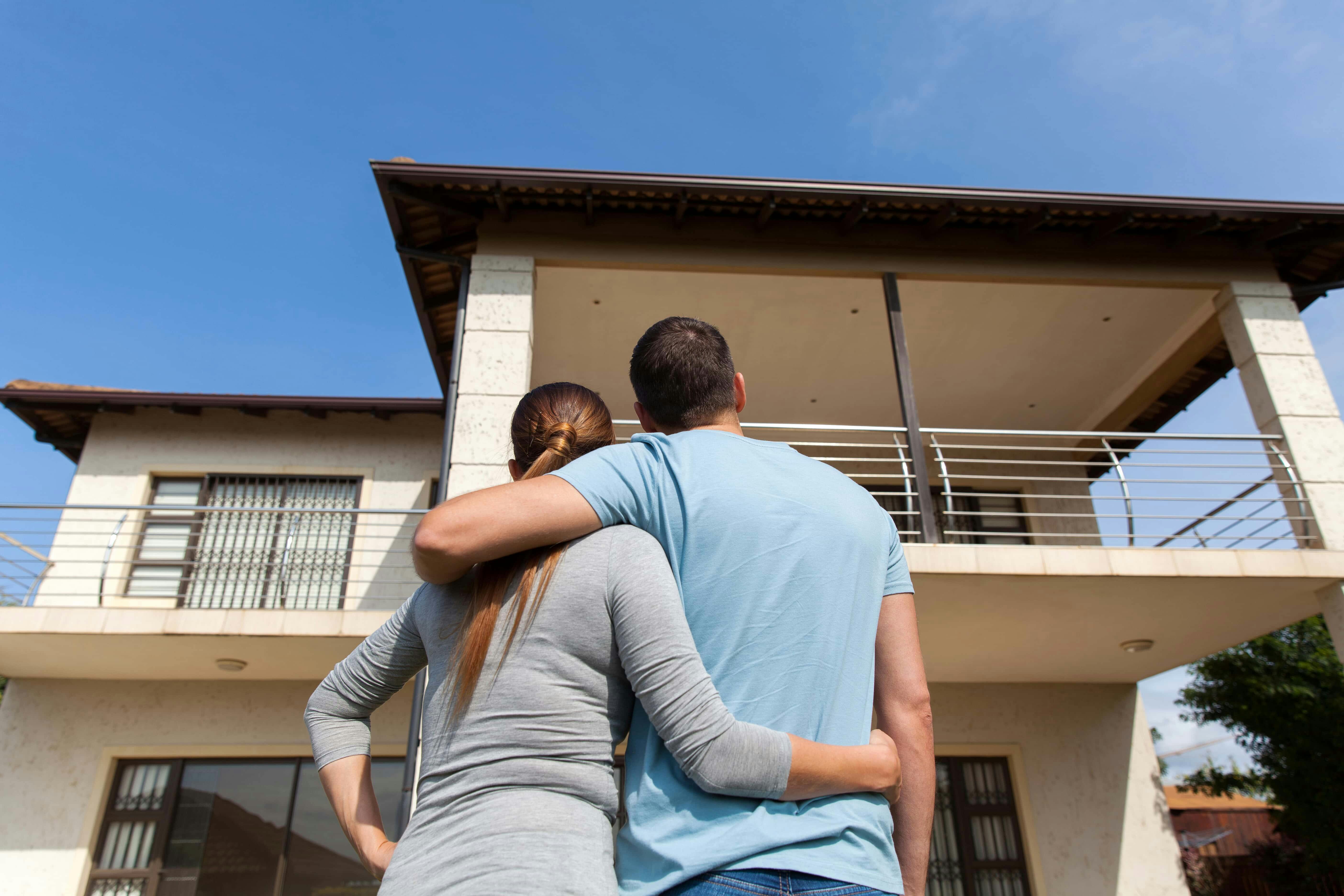 A couple (man and woman) admiring a 2-story Florida house and asking questions before purchasing