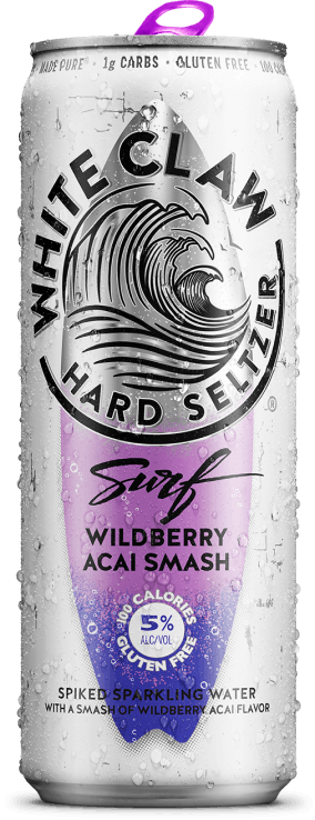 A can of White Claw® Surf Wildberry Acai sits on rocks in front of the sea.