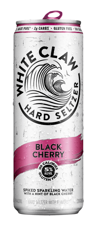 A can of White Claw® Hard Seltzer Black Cherry sits on rocks in front of the sea.