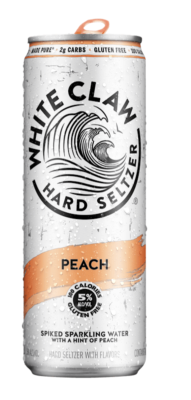 A can of White Claw® Hard Seltzer Peach sits on rocks in front of the sea.
