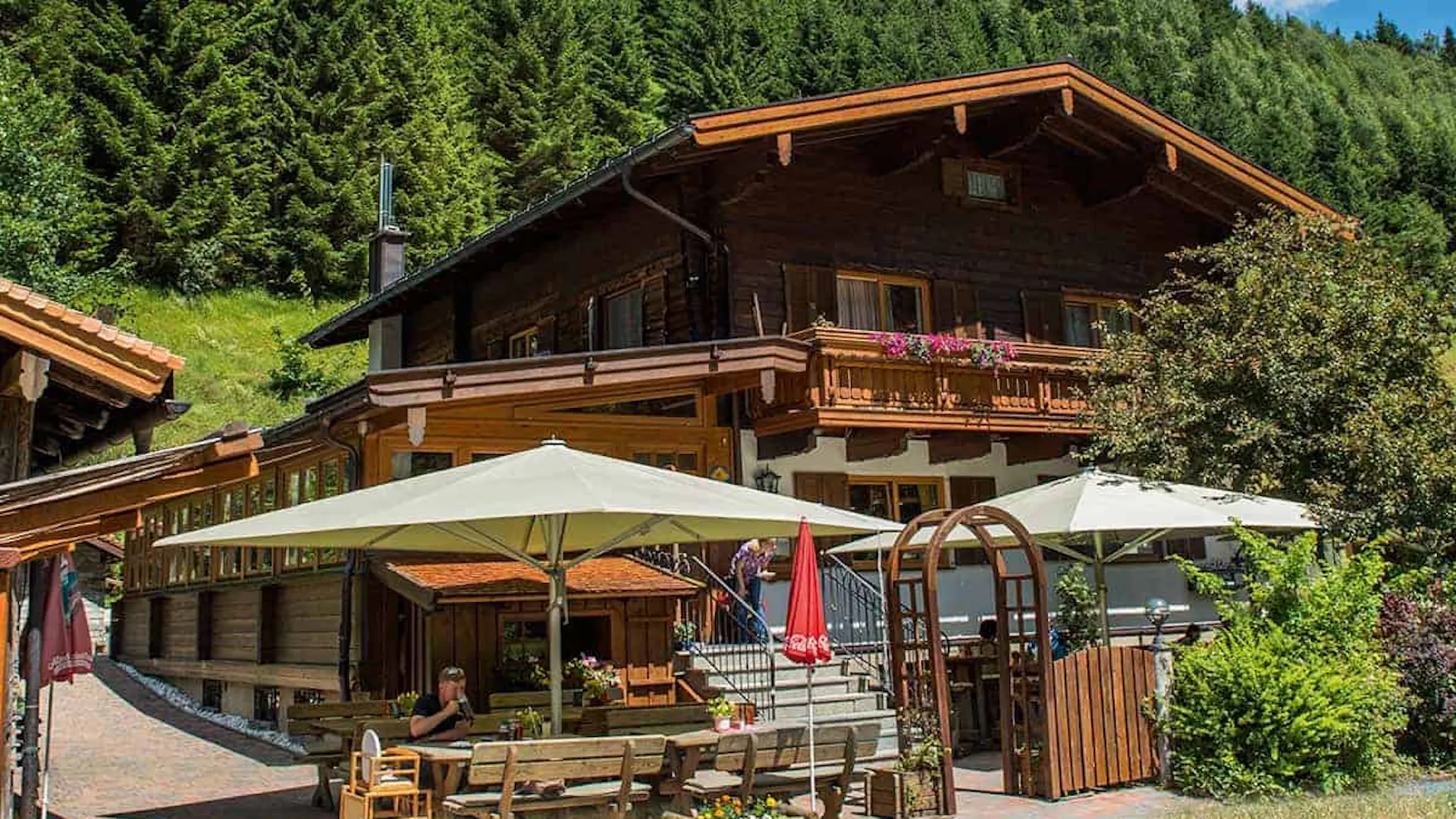 Landgasthaus Weixen in Rauris. Man sieht ein schönes, traditionalles, österreichische Haus am Bild mit Terasse. Finde deine Ferienwohnung bei we.rent