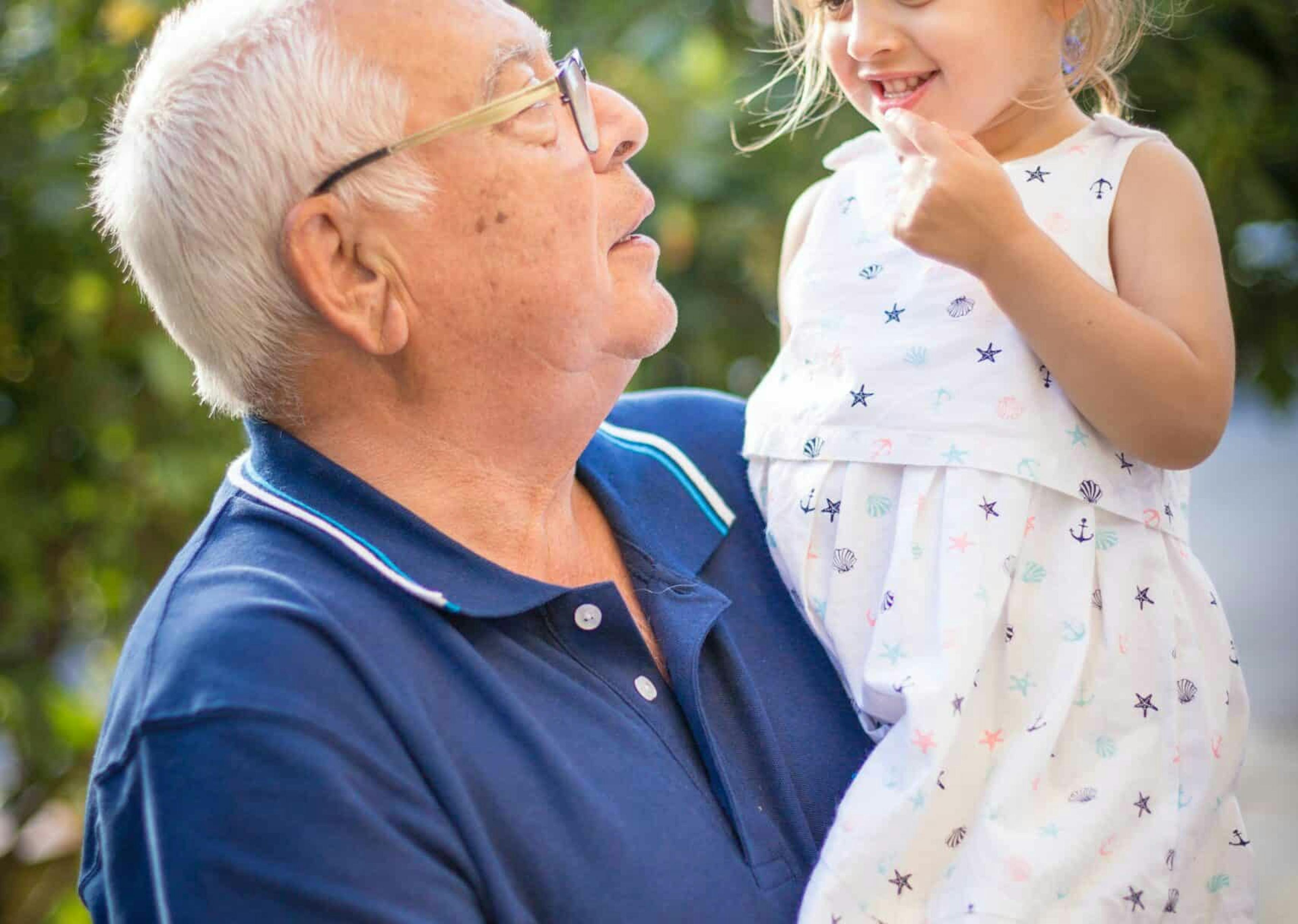 An elderly man carrying a young child