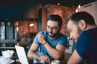 2 men reviewing the process of managing a full-time job and side business on a computer