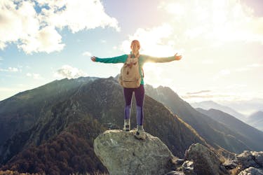 Woman at the top of the mountain shows the results of goal setting