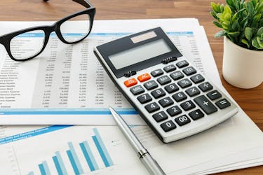 Calculator and glasses can help when you calculating your investment property profit or loss