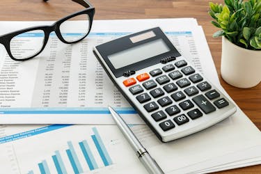 Calculator and glasses can help when you calculating your investment property profit or loss