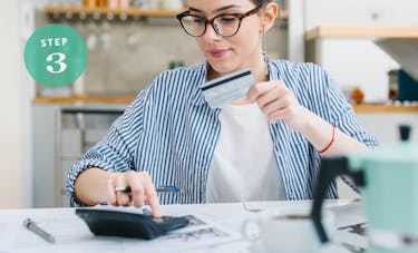 Typing on a calculator while holding a credit card