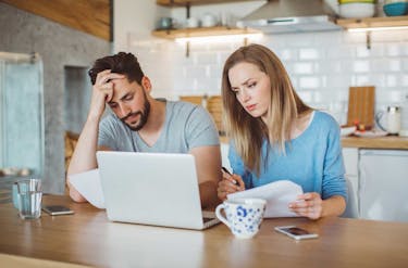 Married couple at a kitchen table looking at how much student debt is owed