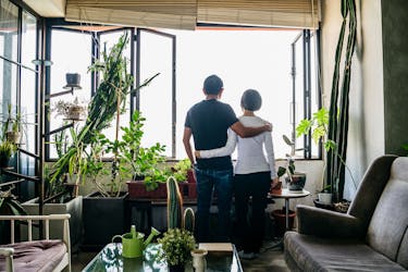 Man and woman looking out a window and talking about helping each other overcome adversity