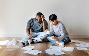 Couple sitting on the floor int heir house looking at their joint debt