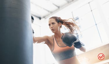 A woman hitting a boxing bag in order to stress less