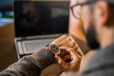 Man is looking at his watch to assess how much time he has left