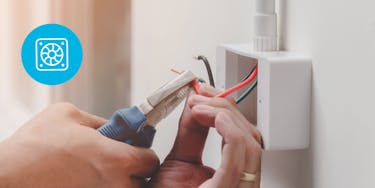 Electrician cutting a red wire inside of a wire box