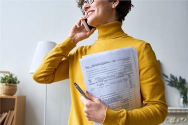 Woman working on her taxes at home while talking on the phone