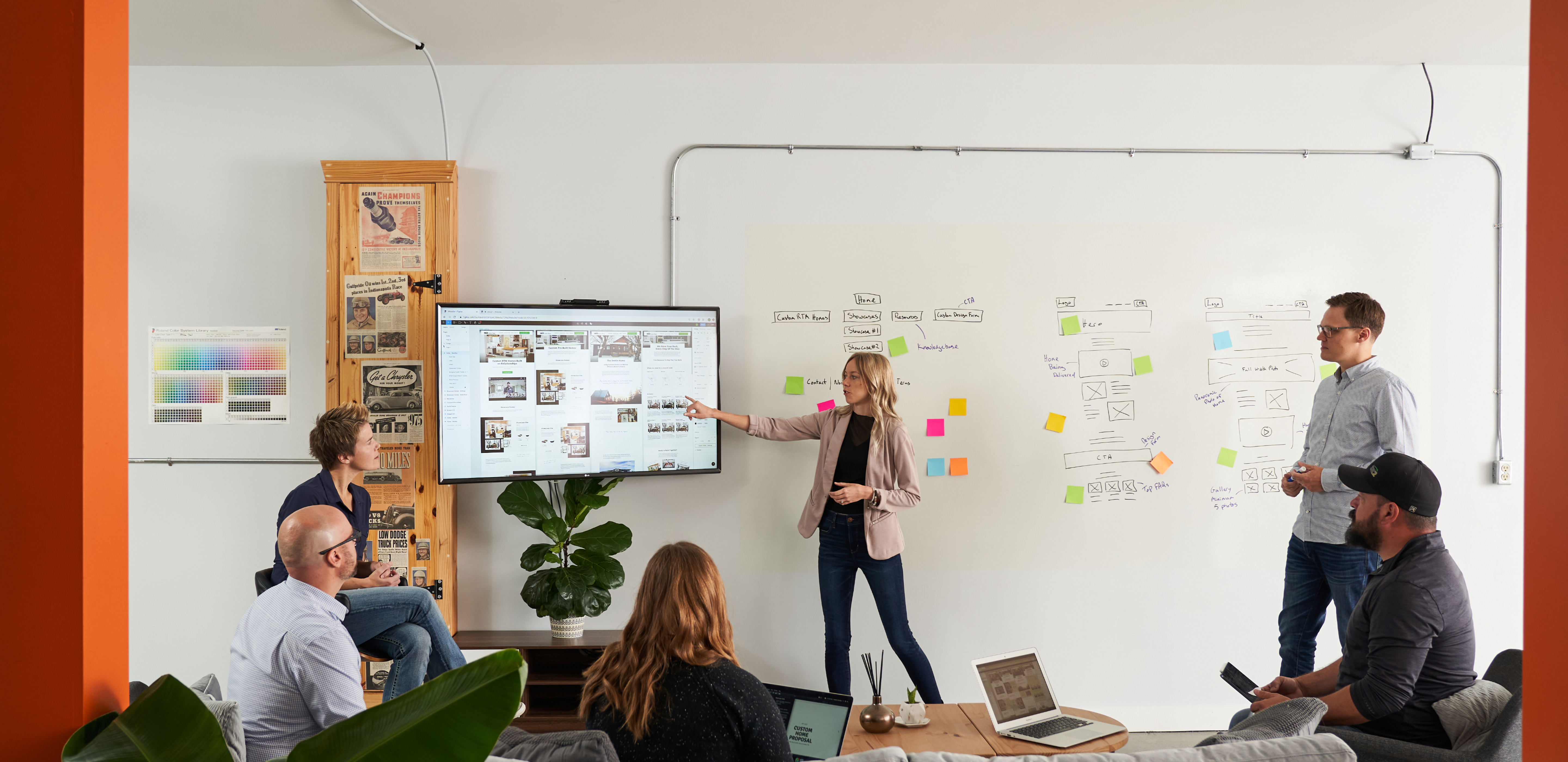 Roadmap team members discuss effective Lead Generation. Sticky notes on a white board demonstrate a Demand Generation Ecosystem in the background. 