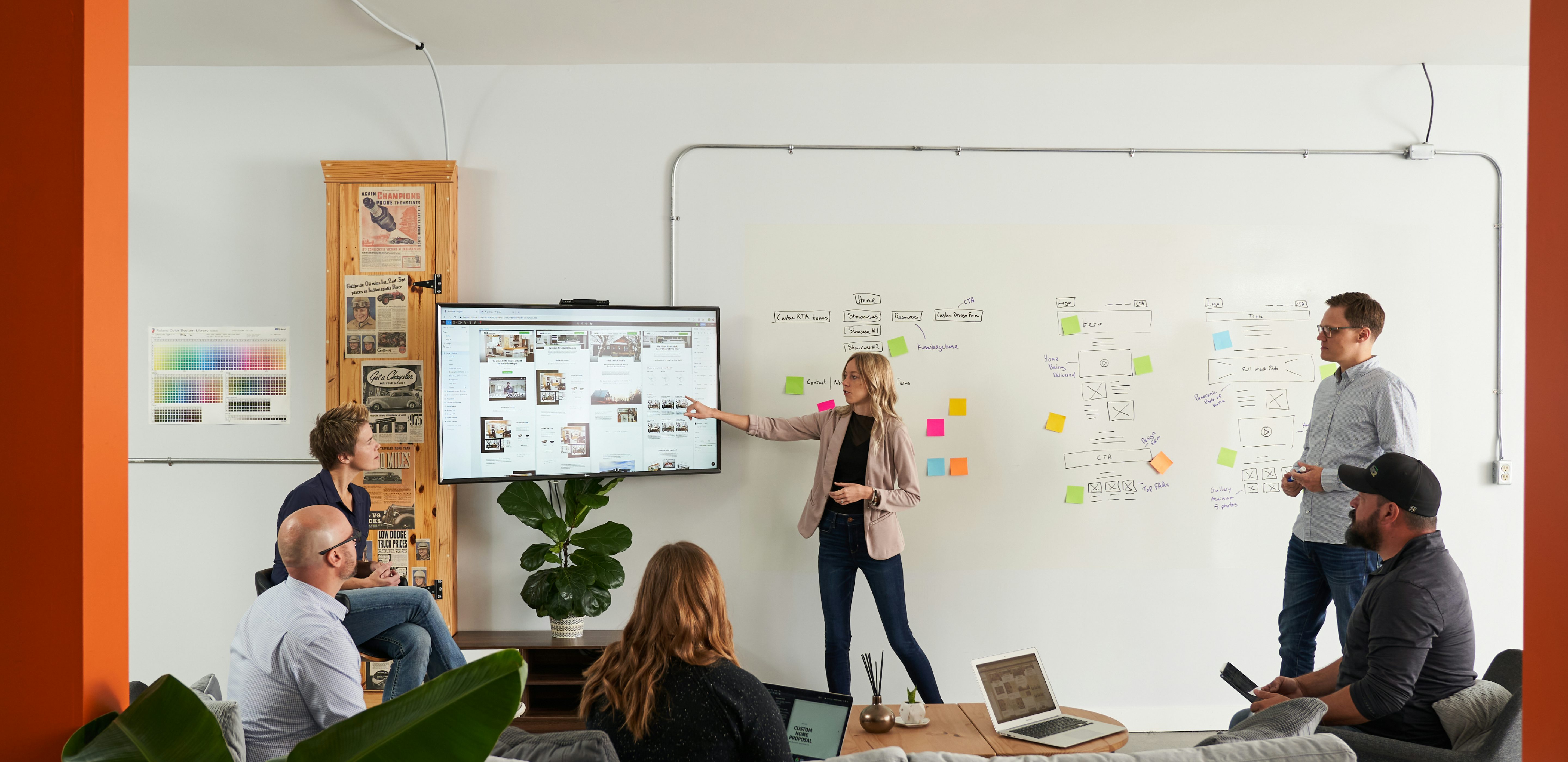 Roadmap team members discuss effective Lead Generation. Sticky notes on a white board demonstrate a Demand Generation Ecosystem in the background.