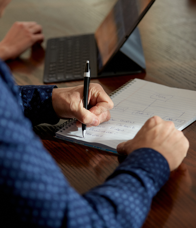 Nick Verwymeren, writing in a notebook. The outline of a website conversion funnel can be seen on the page.