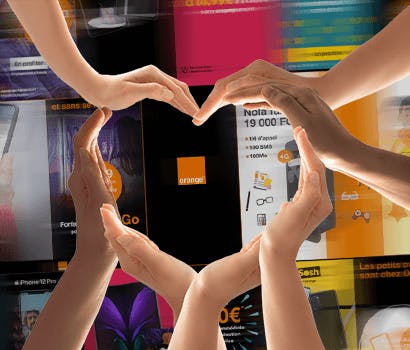 Plusieurs mains forment un coeur devant de nombreuses publicités pour l'opérateur Orange