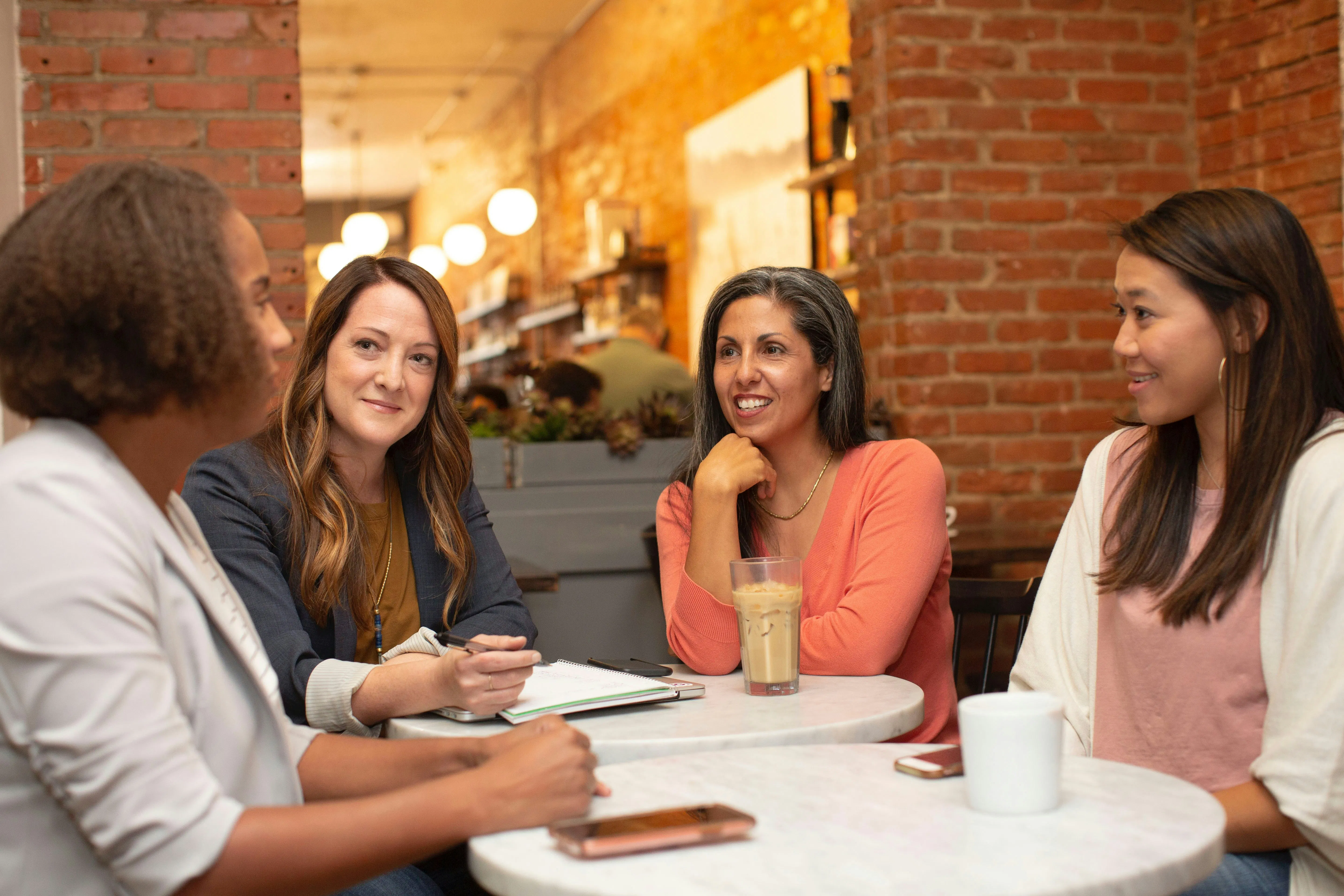 カフェのテーブルでおしゃべりしている4人の女性