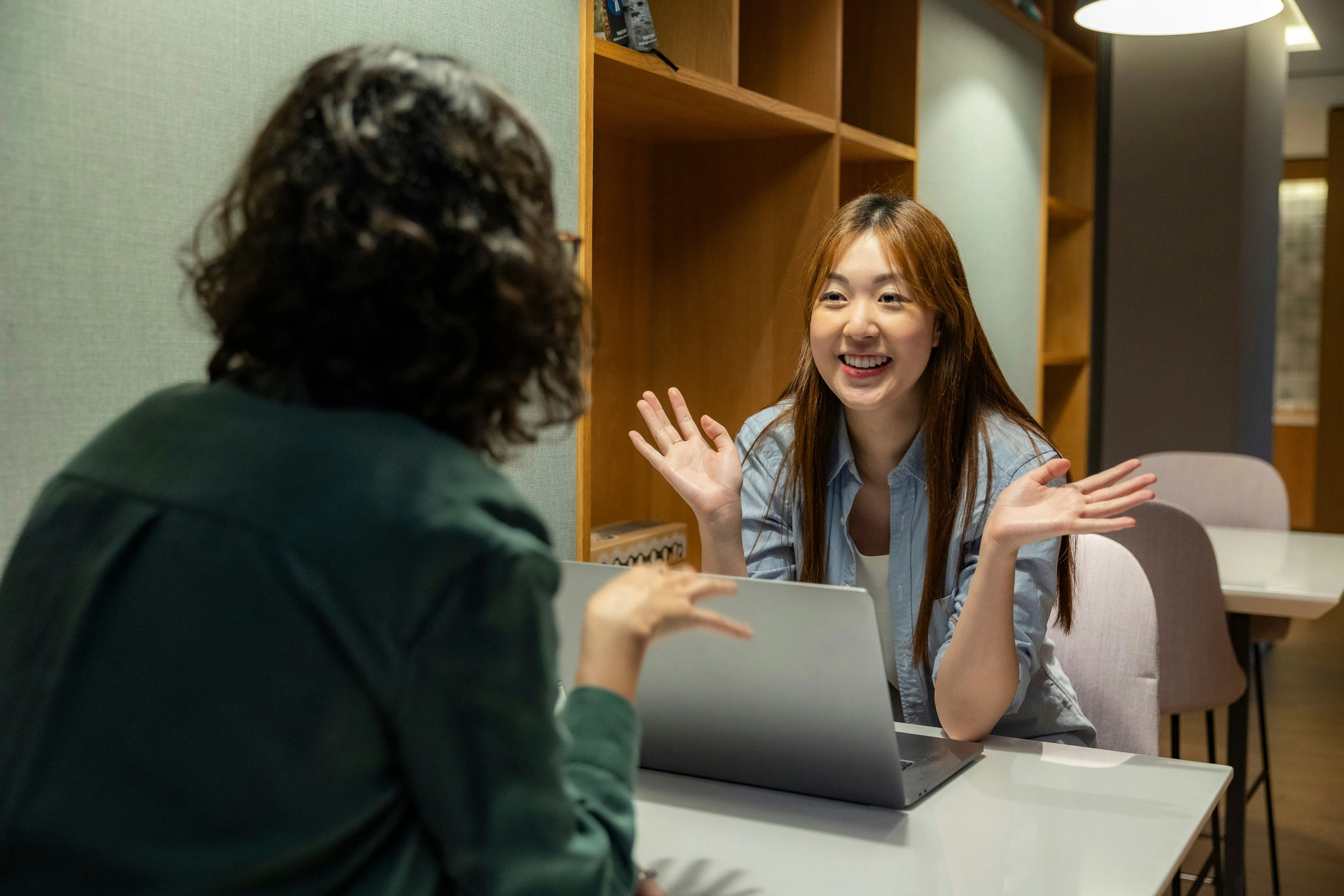 テーブルに座っている女性が別の女性と話している