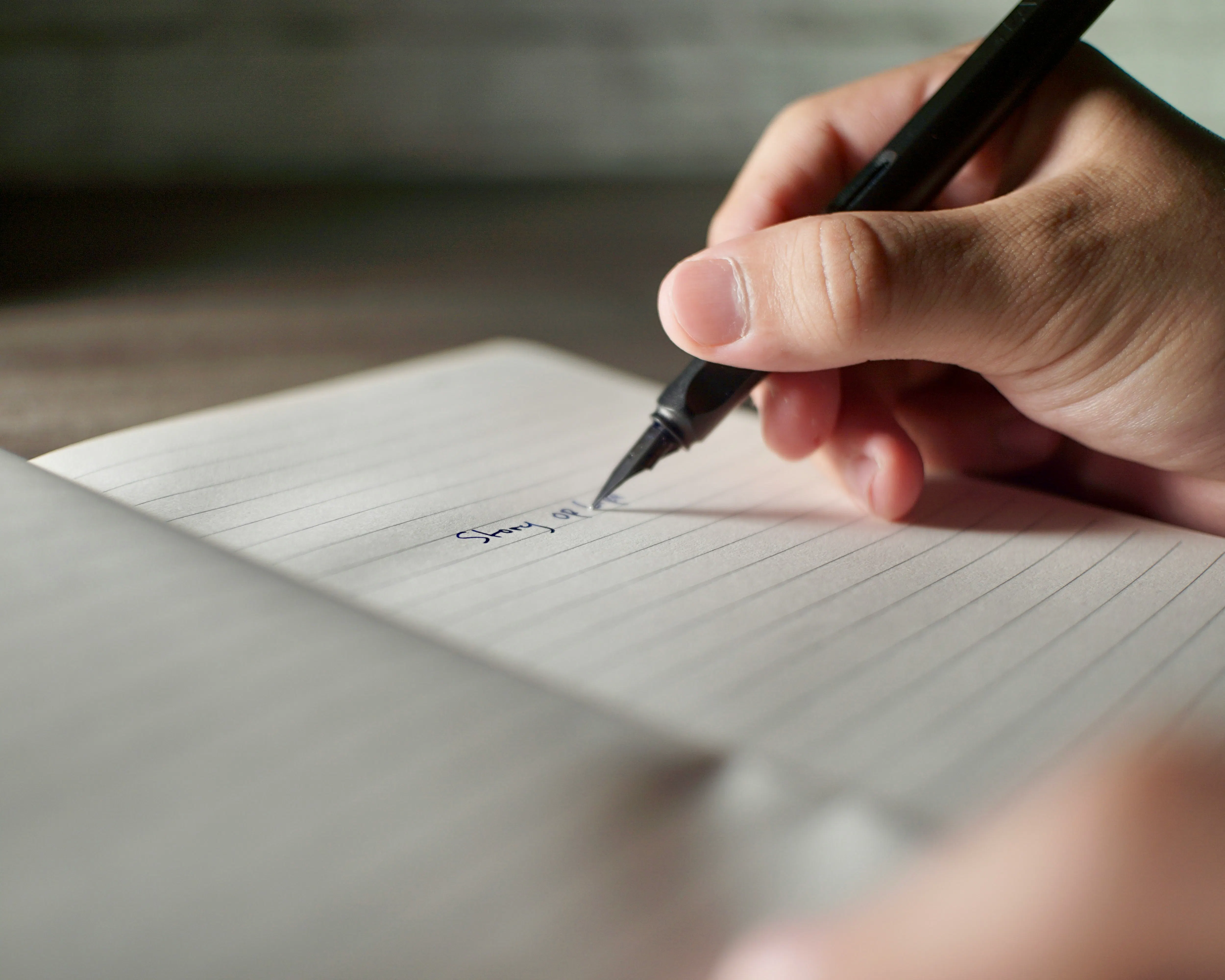 una persona che scrive su un pezzo di carta con una penna