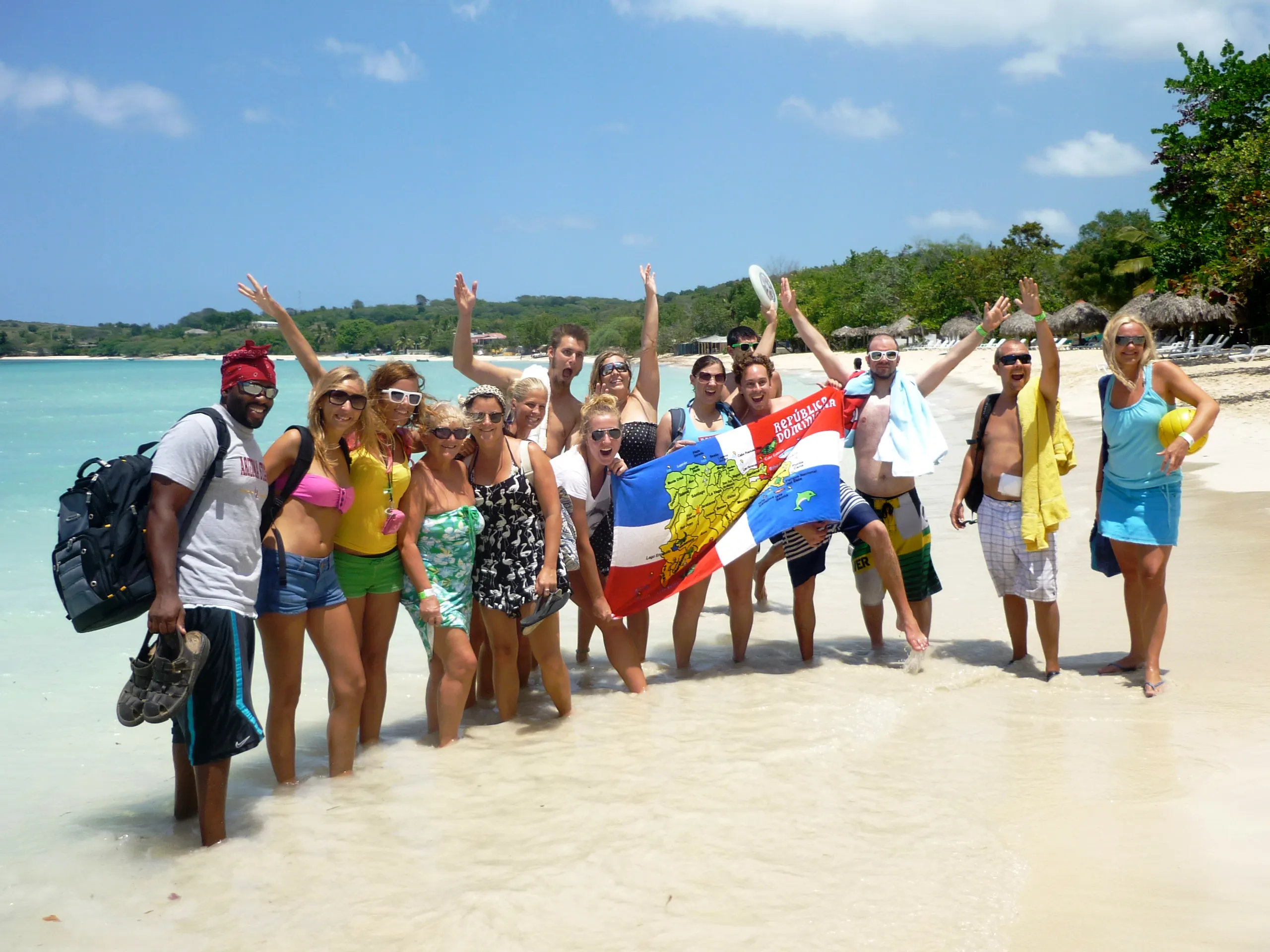 Gruppo di persone che festeggiano sulla spiaggia con bandiere e un'atmosfera tropicale