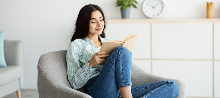 mulher lendo um livro sentada em um sofá de couro preto de 3 lugares