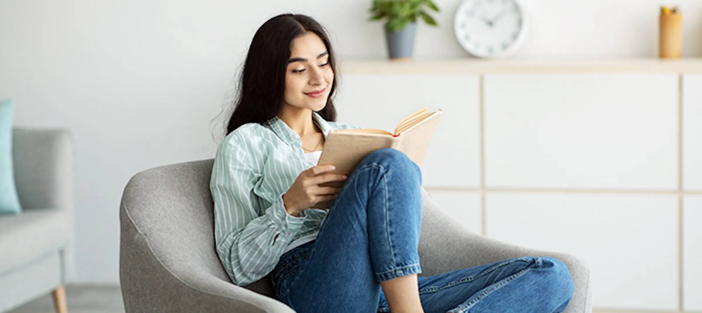 mulher lendo um livro sentada em um sofá de couro preto de 3 lugares