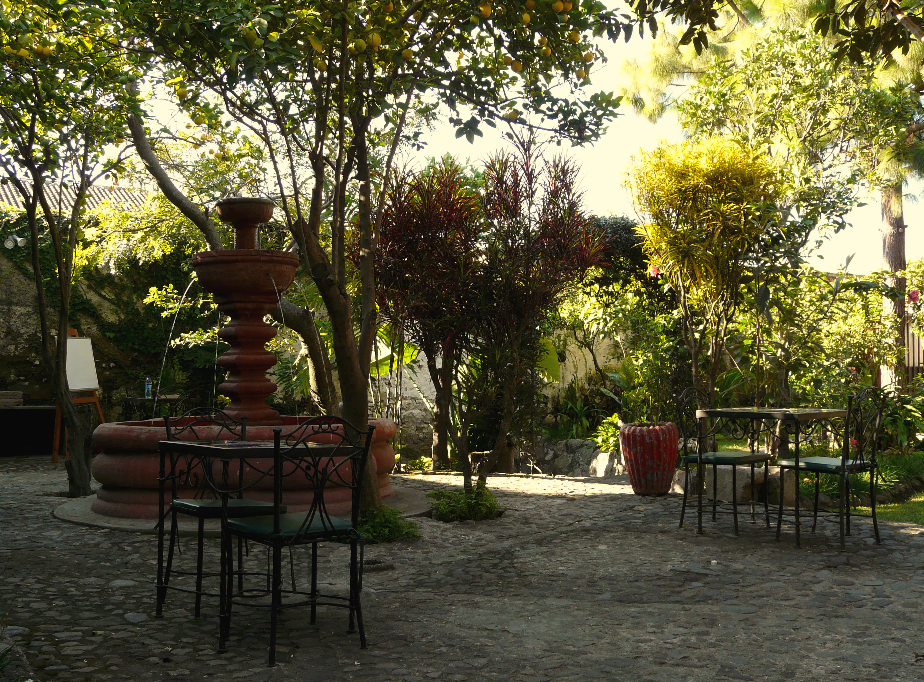 Giardino tropicale con fontane, tavoli all'aperto e aree relax circondate dalla natura