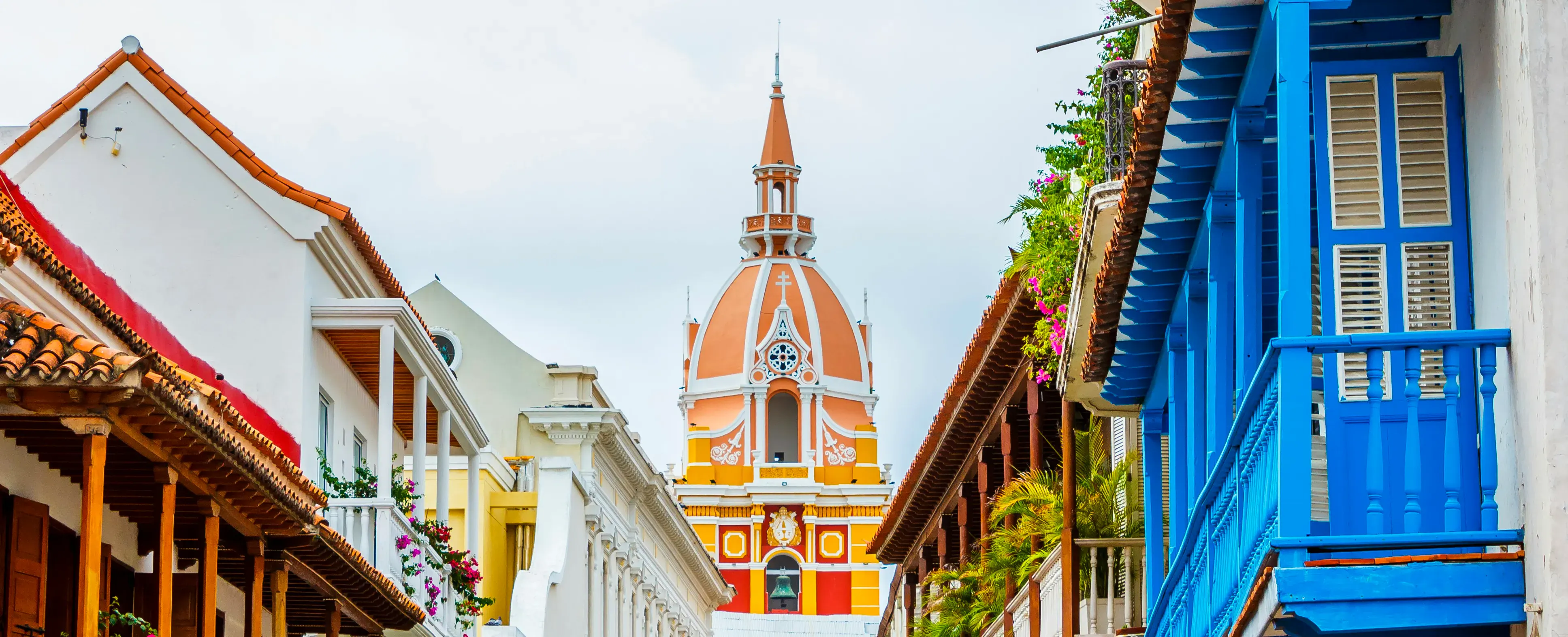 Strada coloniale a Cartagena de Indias con balconi colorati e una cattedrale sullo sfondo