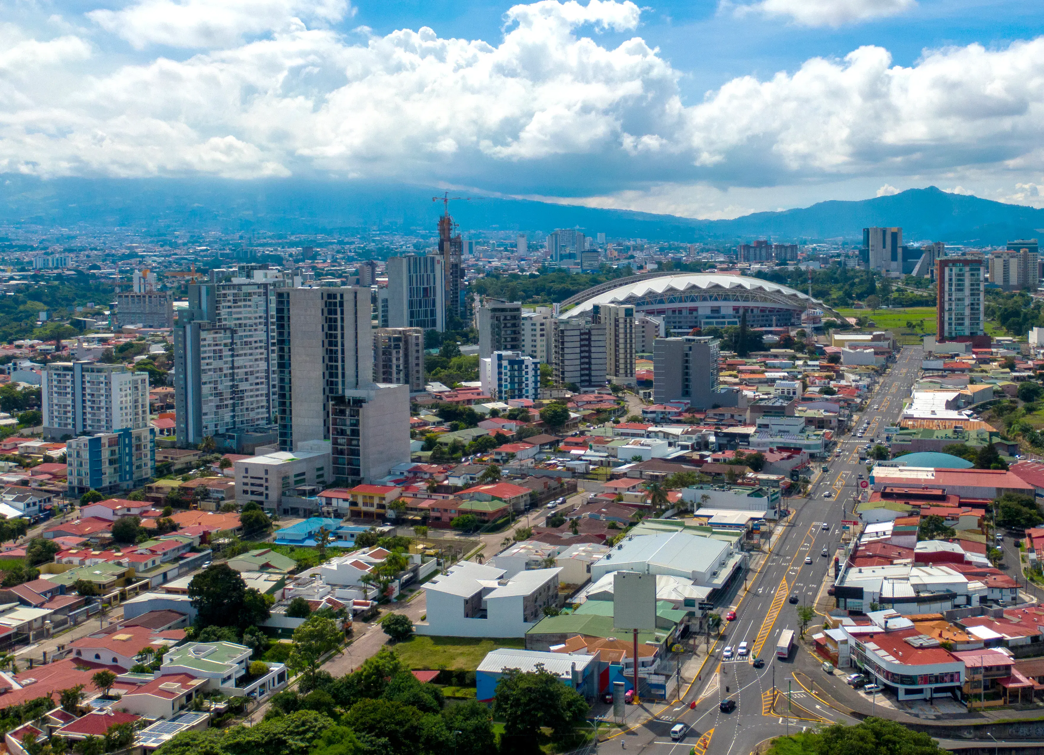Modern city with skyscrapers, avenues, and mountains in the background under a clear sky