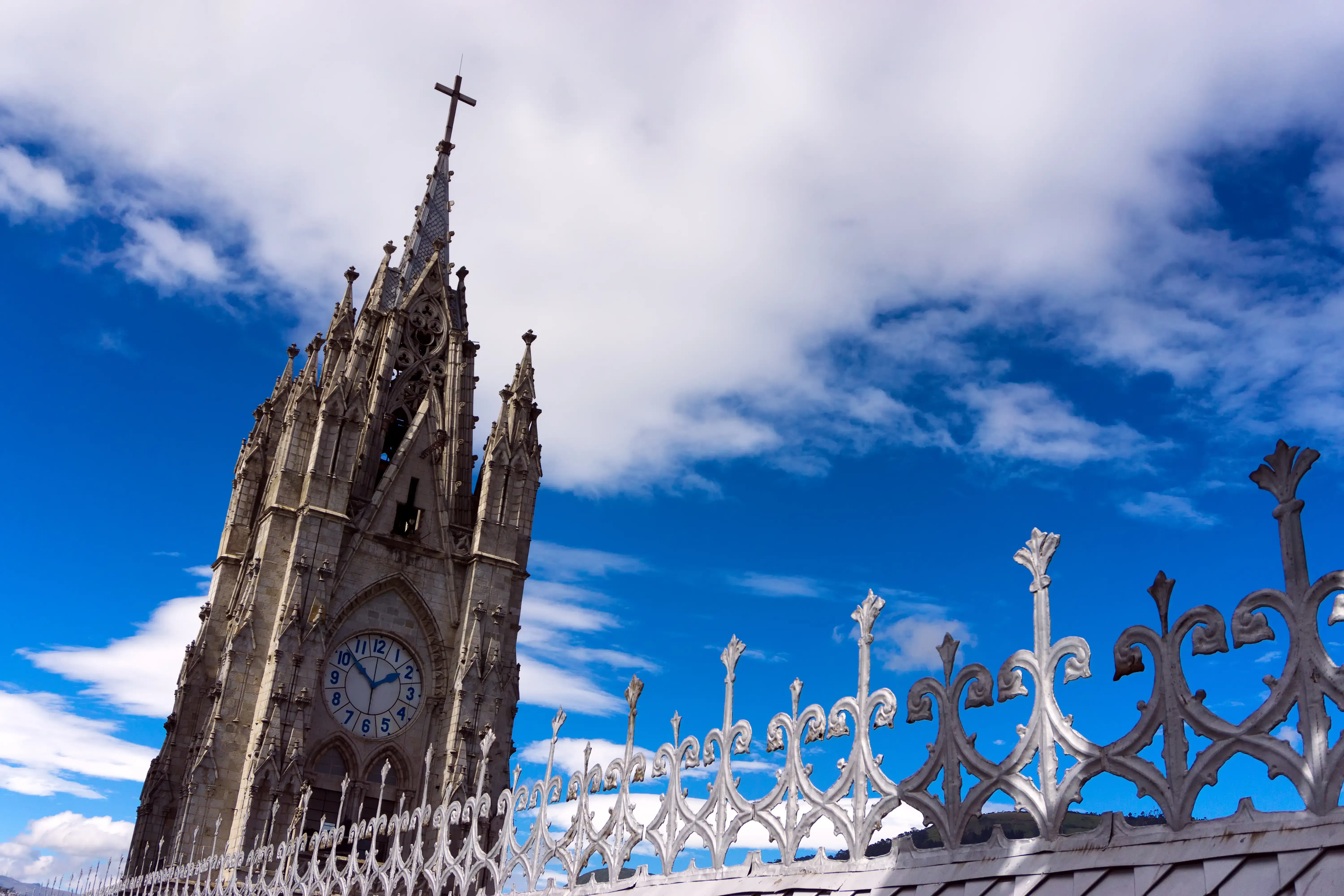 Neugotische Basilika in Quito mit historischen Türmen unter blauem Himmel und Wolken