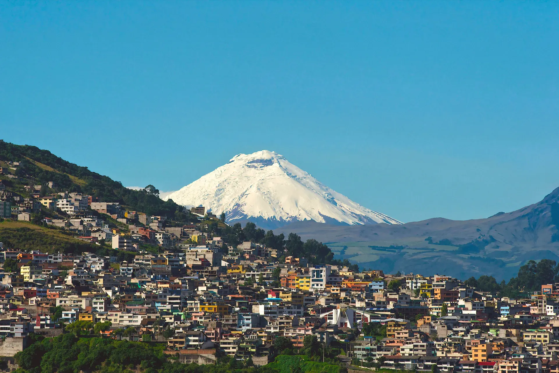 View of Quito with the snowcapped Cotopaxi volcano in the background under clear skies