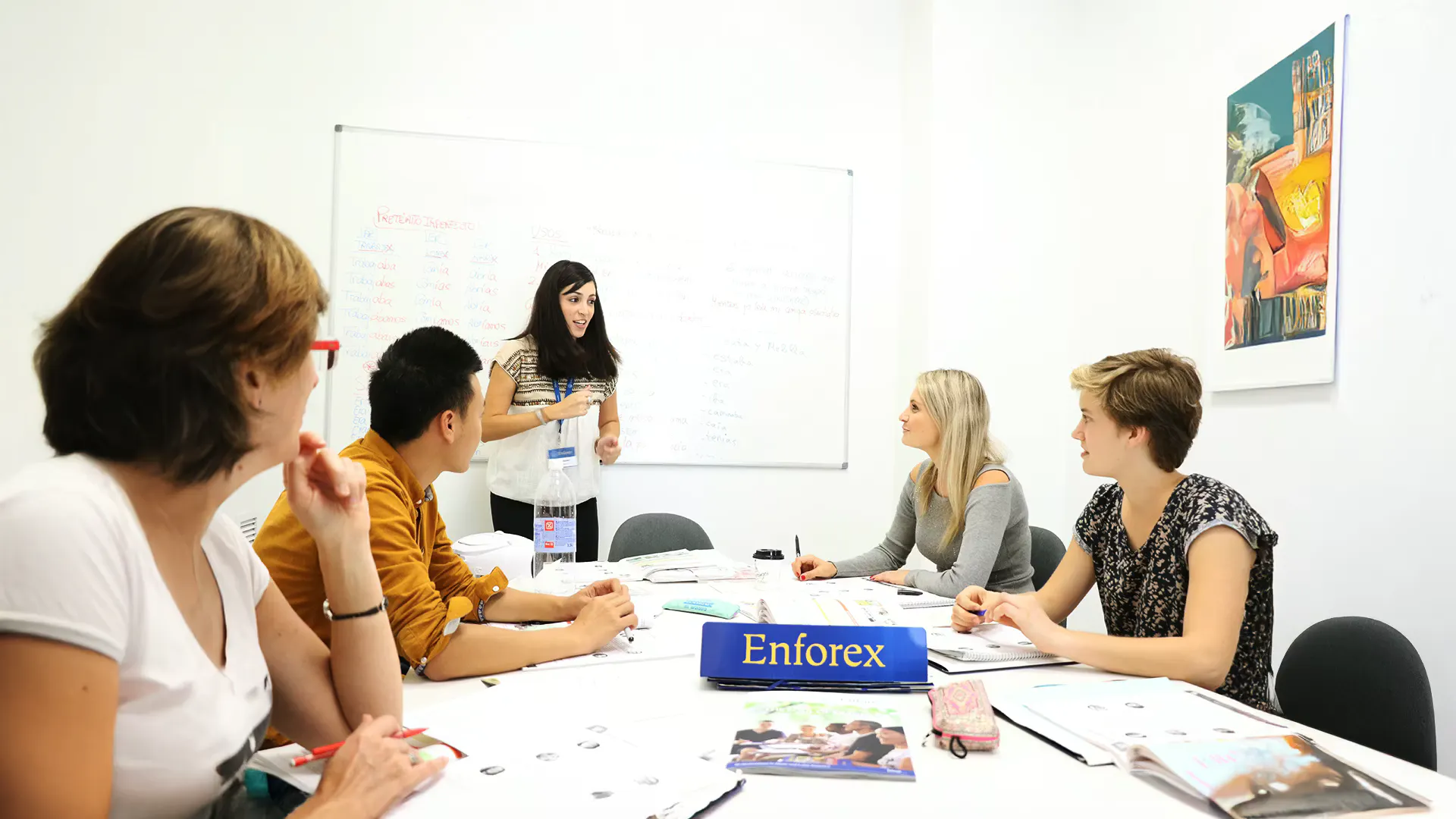 Small multicultural group class with students and a teacher at an Enforex school, learning together in an interactive classroom setting