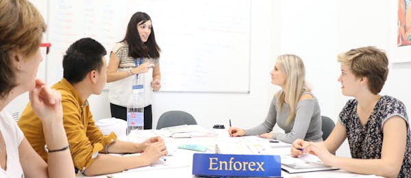 Aula em uma turma pequena e multicultural, com alunos e um professor em uma escola da Enforex, aprendendo juntos em um ambiente interativo.