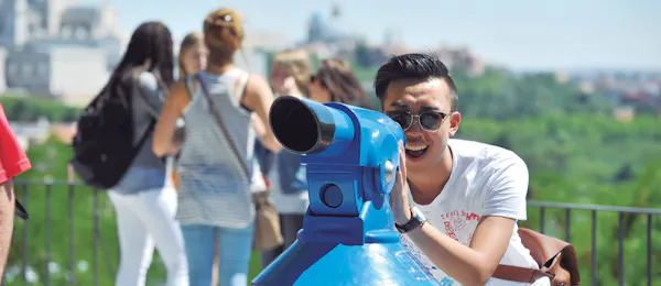 Jovem olhando através de um telescópio em um mirante em Madrid, Espanha, representando uma atividade de passeio turístico e vistas panorâmicas da cidade