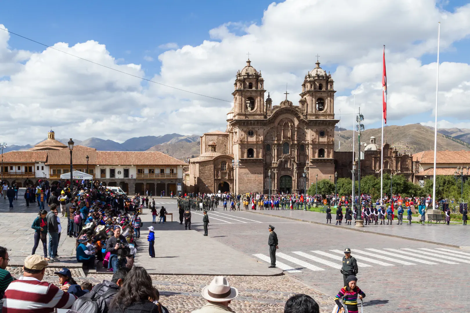 Historic square in Cusco with a colonial cathedral and people walking through the city center