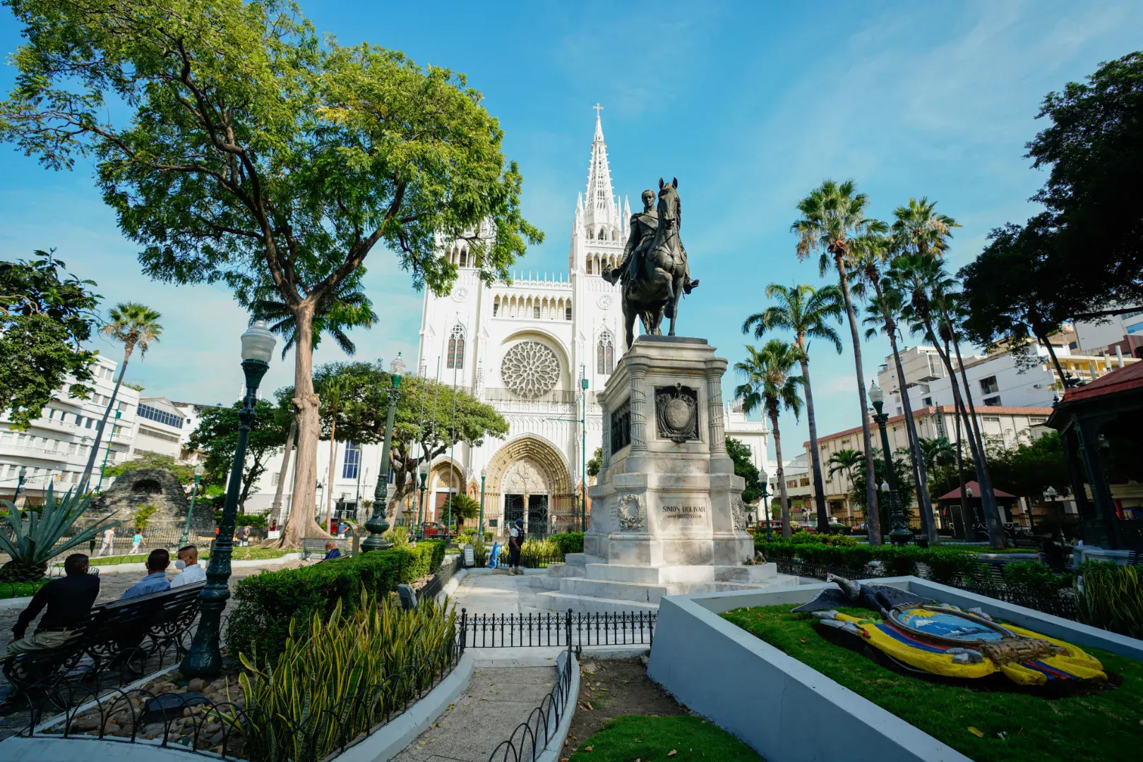 Piazza storica in Ecuador con una chiesa, un monumento e giardini circondati da palme