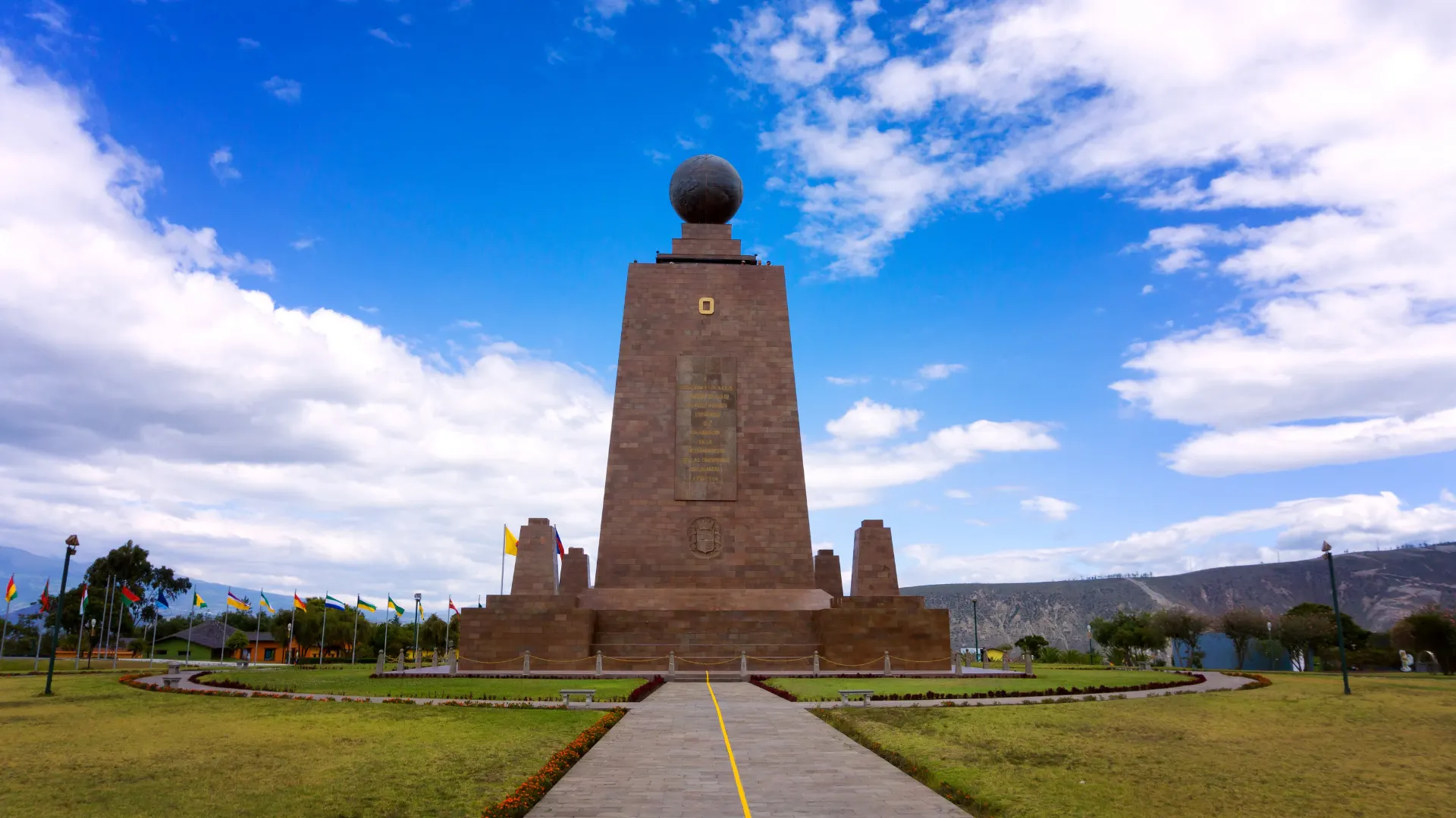 Mitten der Welt-Denkmal in Quito unter blauem Himmel mit Bergen im Hintergrund