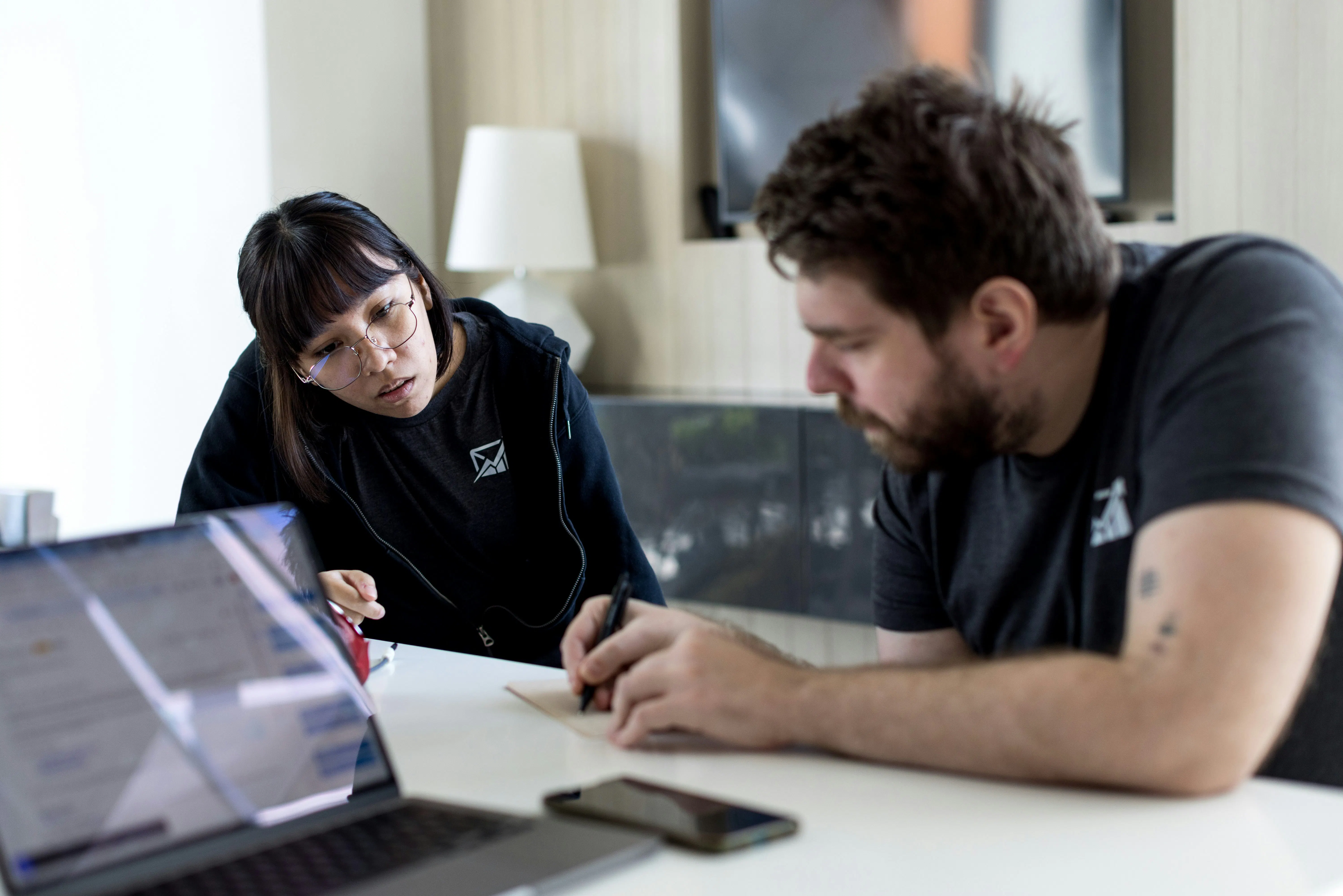 Um homem e uma mulher sentados à mesa com um notebook
