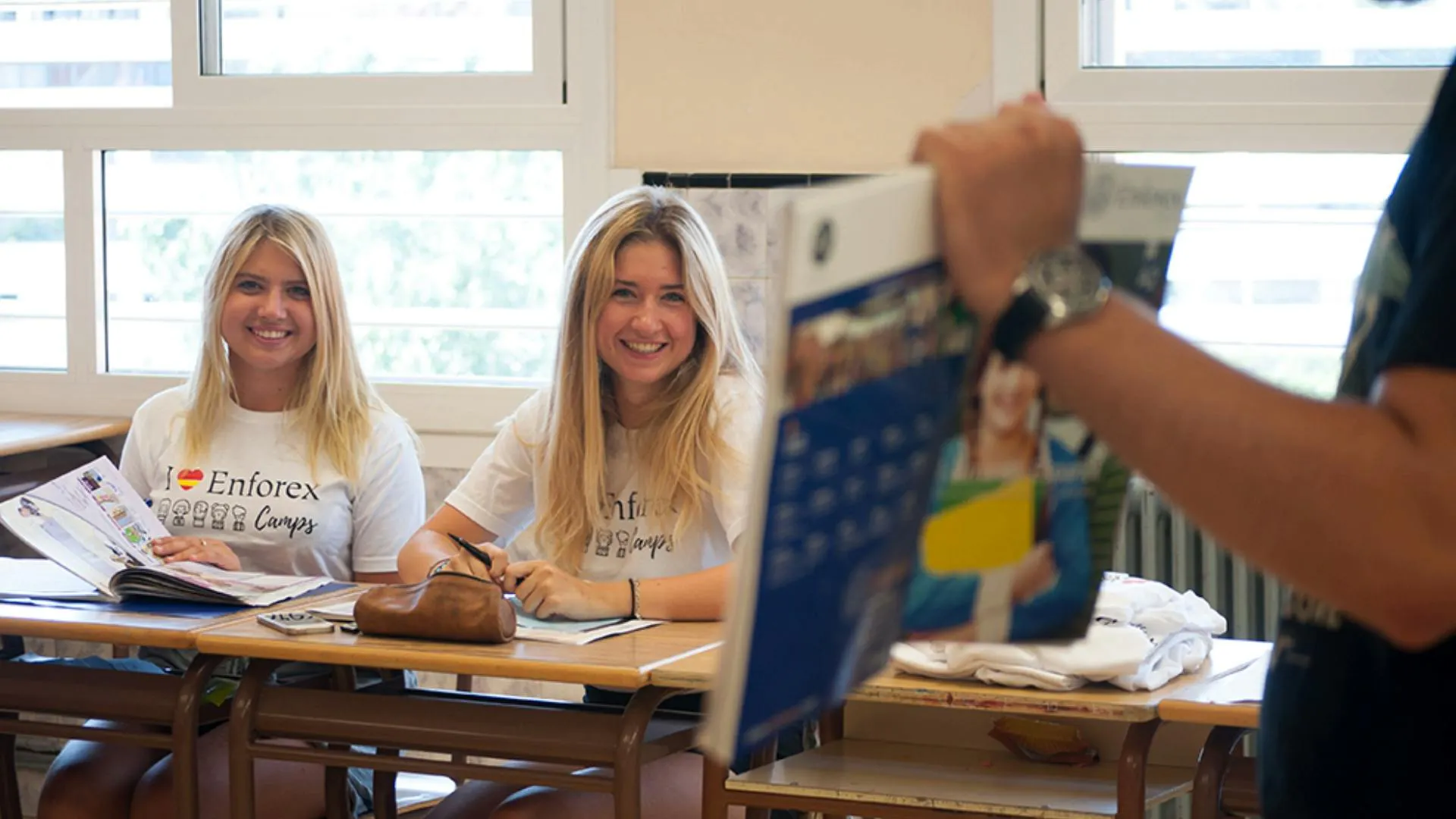 Insegnante che insegna spagnolo a due ragazze usando un libro in un’aula del camp