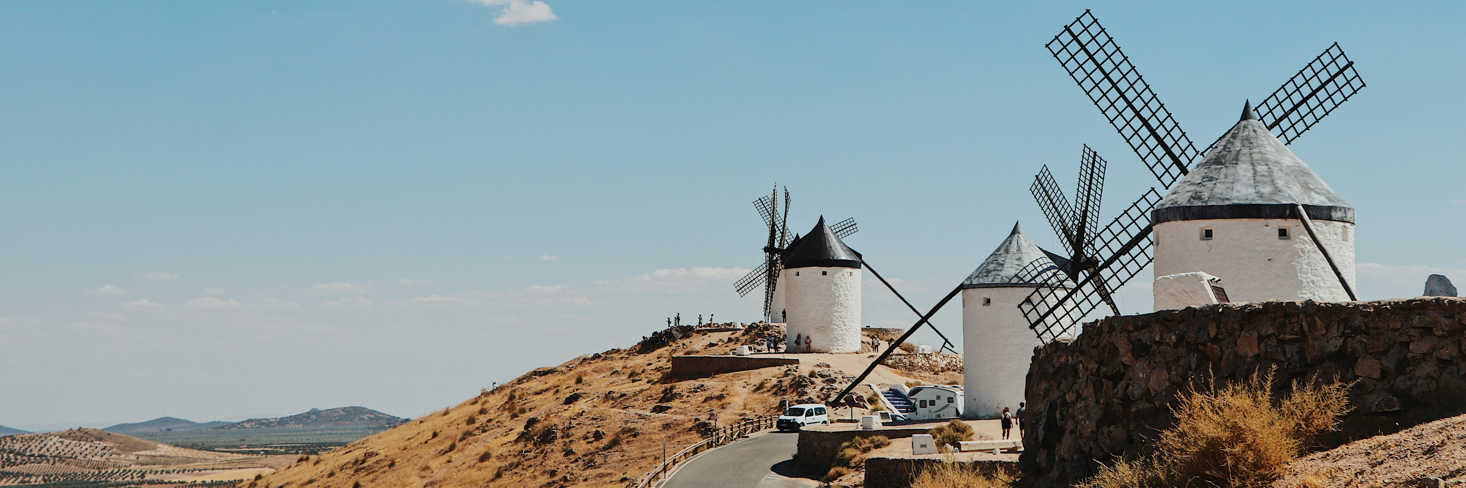 white windmill on brown field under blue sky during daytime