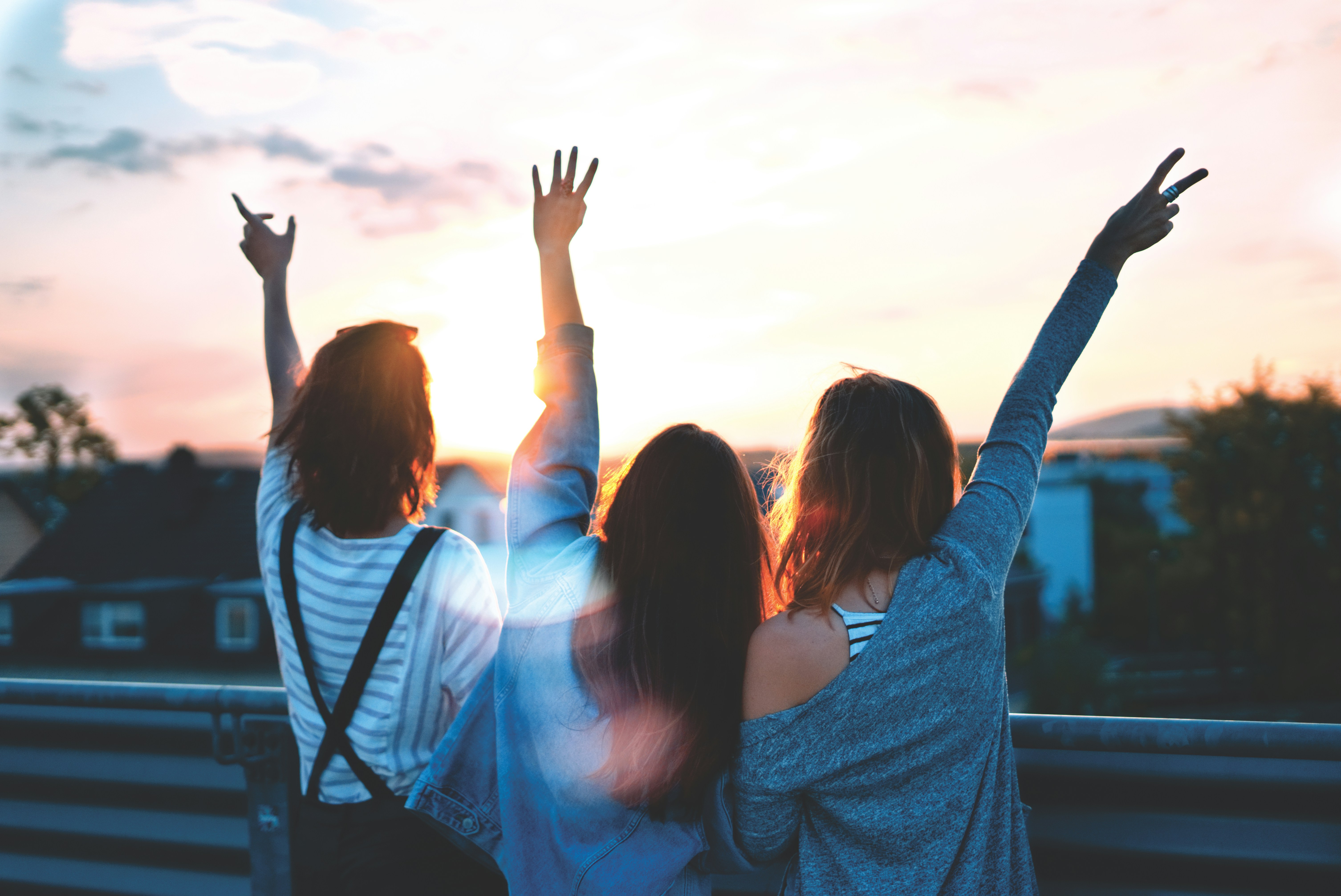 foto di tre donne che alzano le mani \