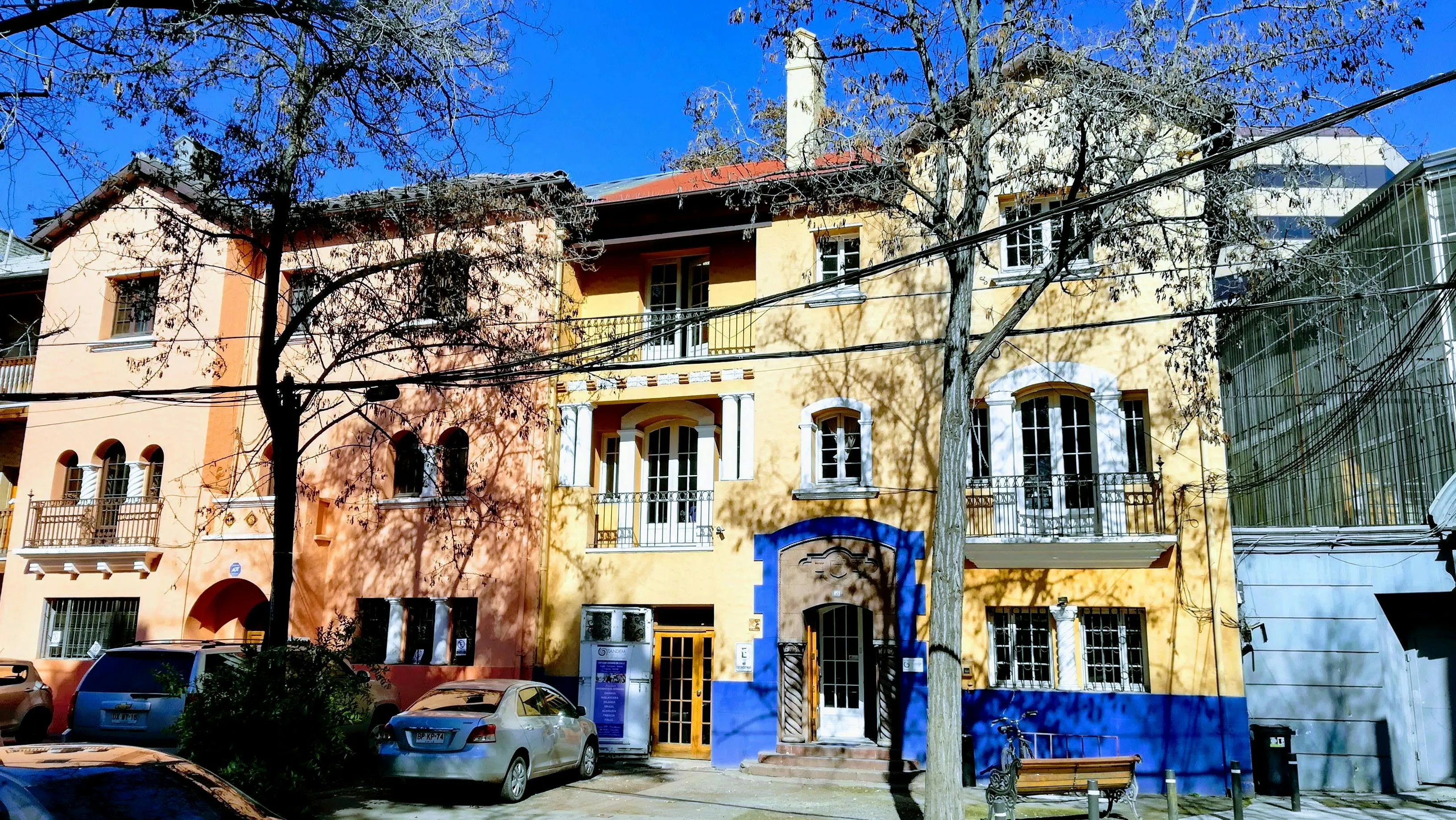 Facciate di edifici residenziali colorate su una strada urbana con alberi e balconi