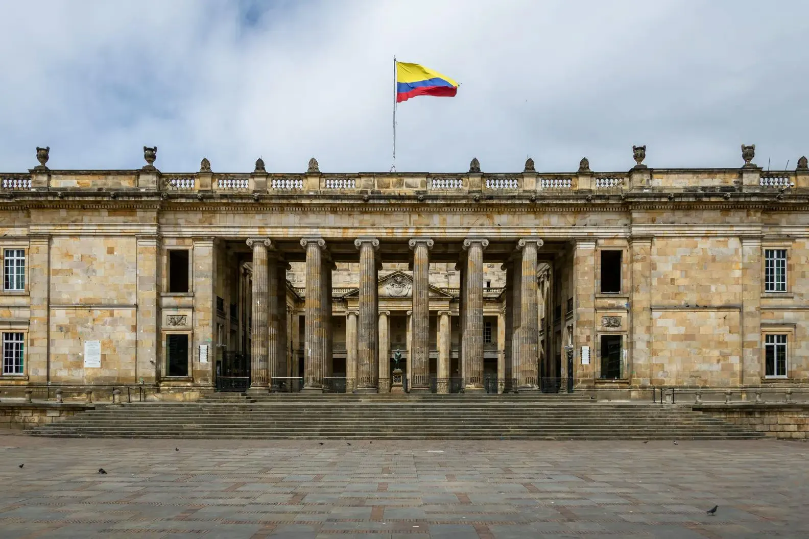 Edificio governativo con colonne classiche e la bandiera colombiana in una piazza storica