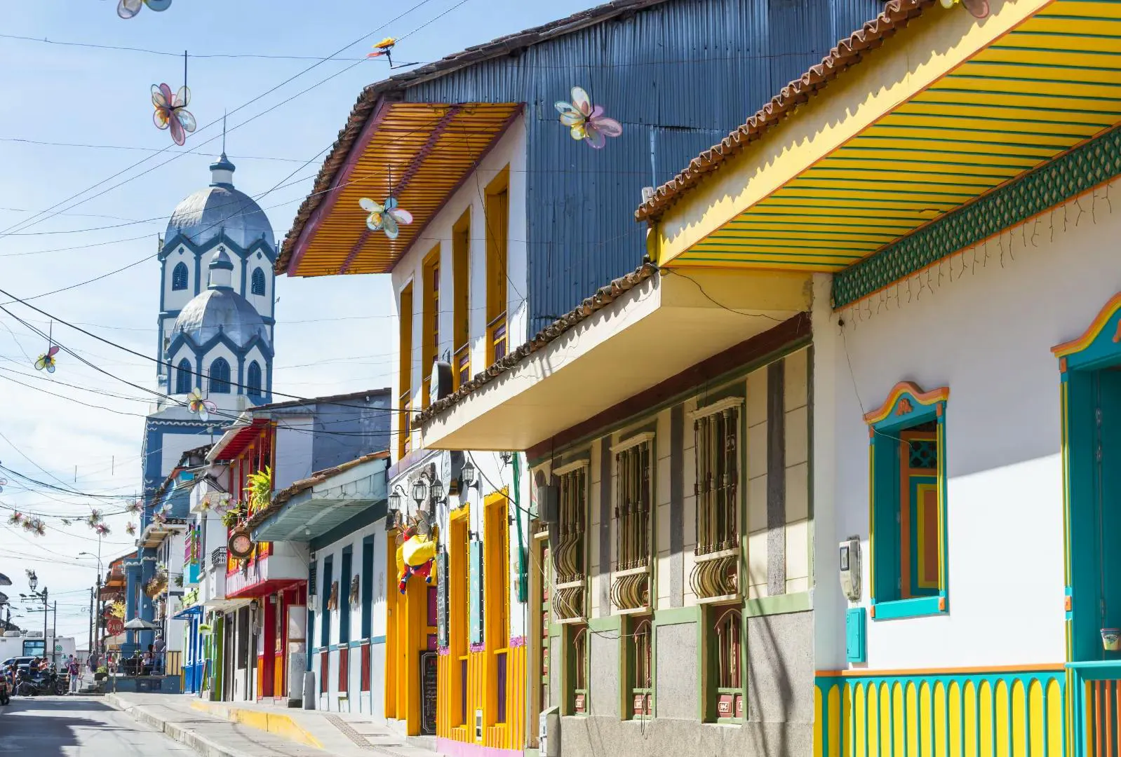 Strada colorata in Colombia con architettura tradizionale e una chiesa sullo sfondo