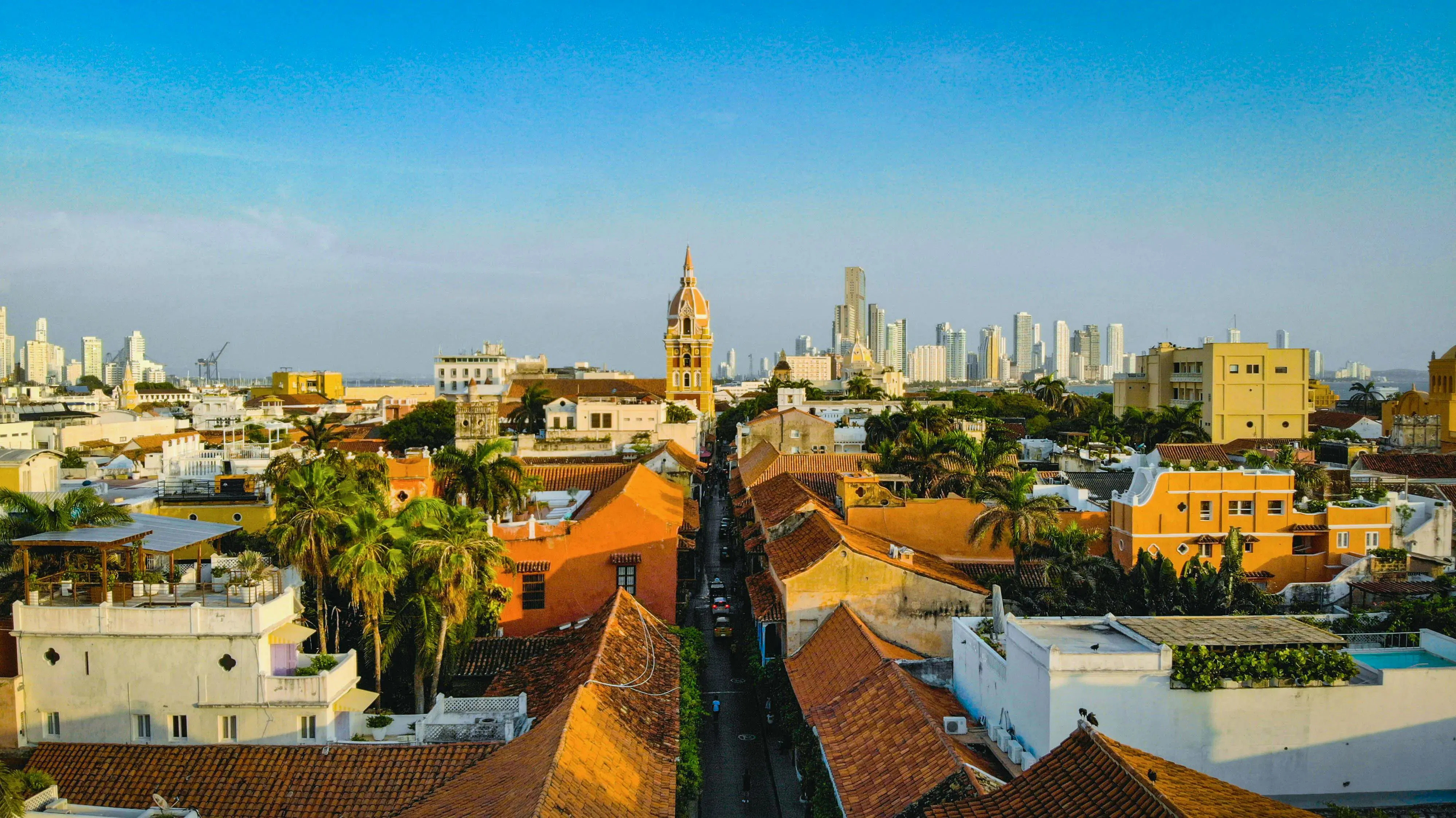 Vista panoramica di una città coloniale con tetti colorati e grattacieli sullo sfondo