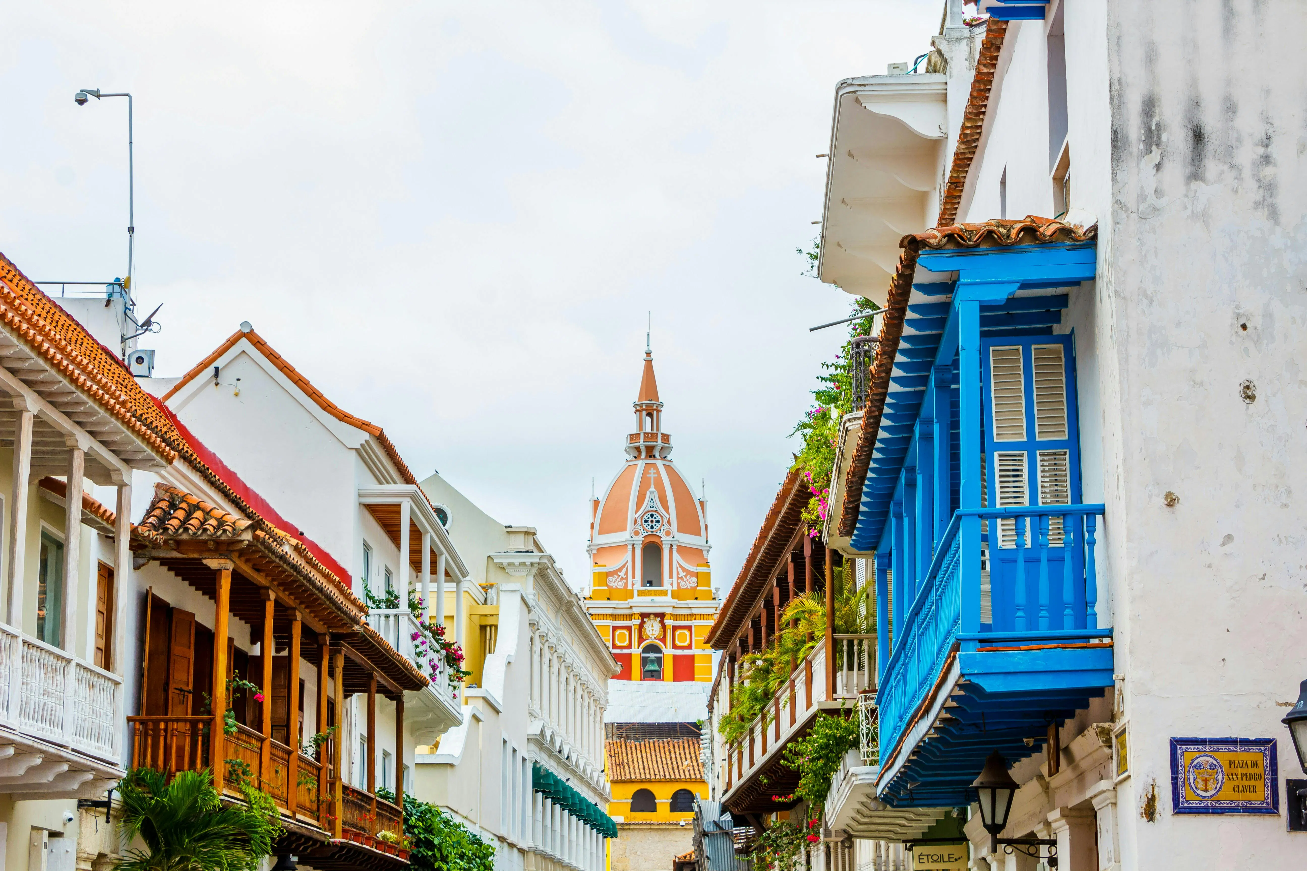 Strada coloniale con balconi colorati e una cattedrale sullo sfondo di una città storica
